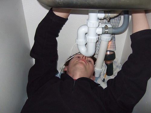 Man under sink, with pvc pipes